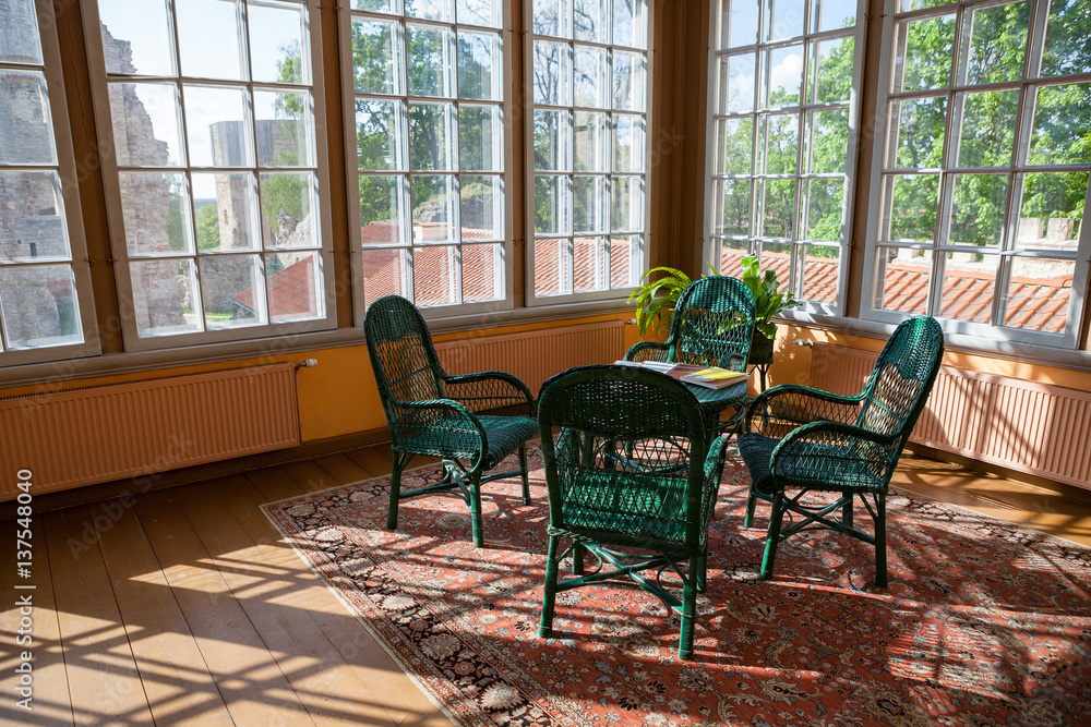 Fototapeta premium Bright room in cottage with wicker rattan chairs and table. Big windows and sunlight.
