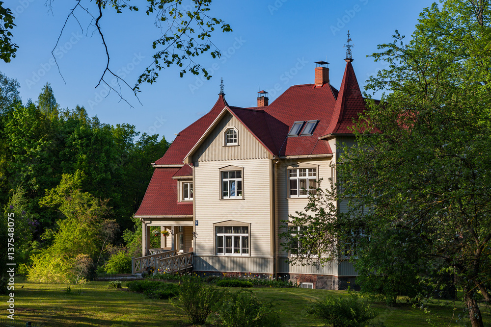 Big traditional Baltic style wooden cottage. Greenery and summer daytime.