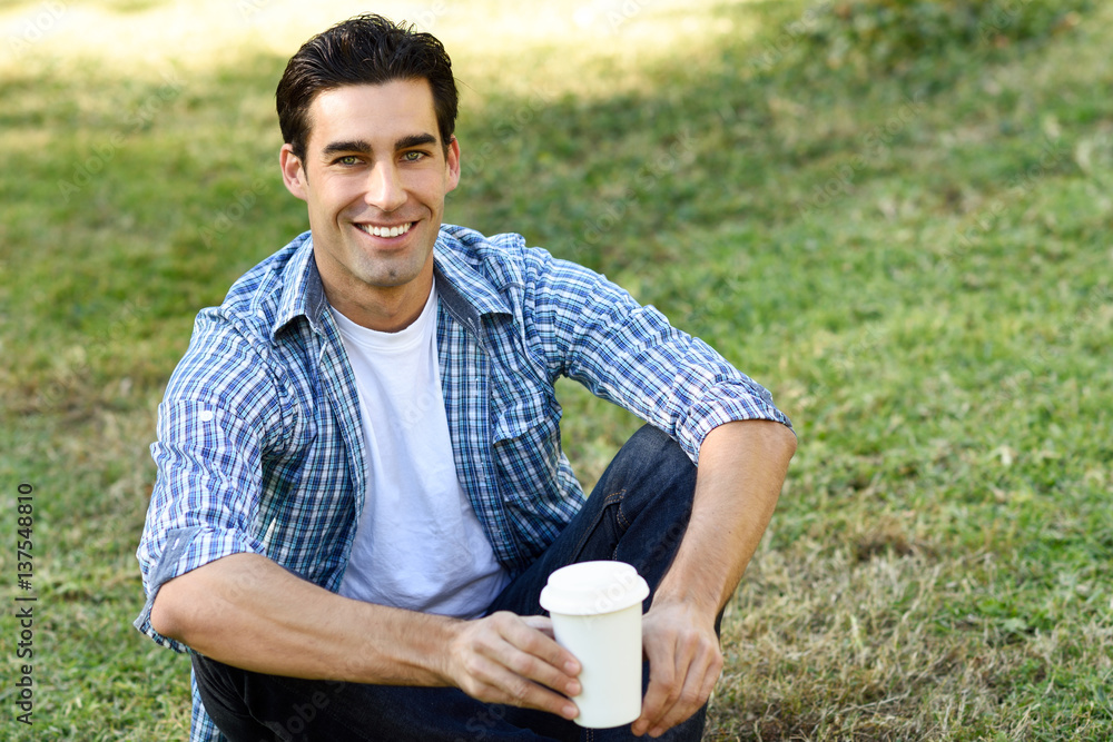Man drinking coffee to go in an urban park Man drinking coffee to go in an urban park