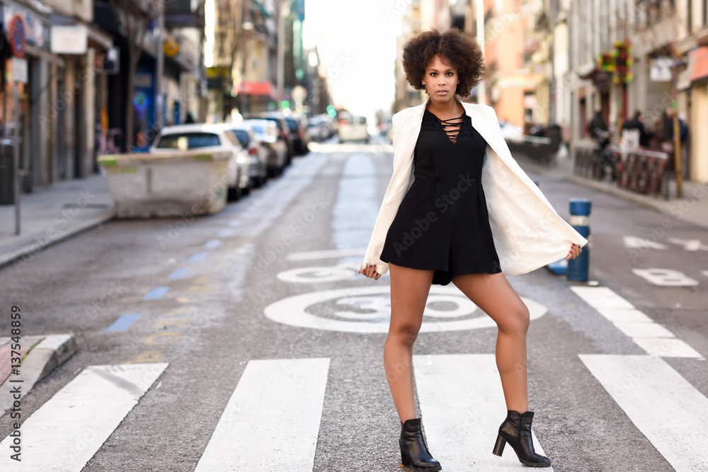 Young black woman with afro hairstyle standing in urban background Young black woman with afro hairstyle standing in urban background