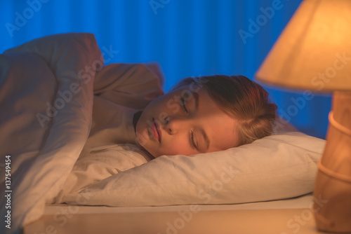 The cute girl sleeping on the bed. Evening night time