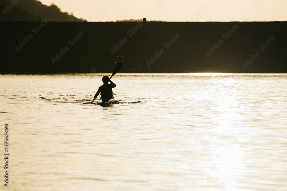 Female canoer rowing in the morning sun