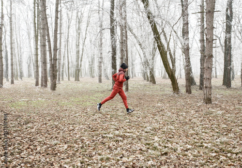 Side view of young sportsman running in misty winter forest. © Zoran Zeremski