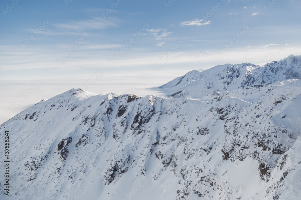 Aerial shot of snowy mountain range on a sunny winter day