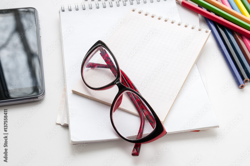 Business still-life, glasses, smart phone, notebook and colored pencils Business still-life, glasses, smart phone, notebook and colored pencils