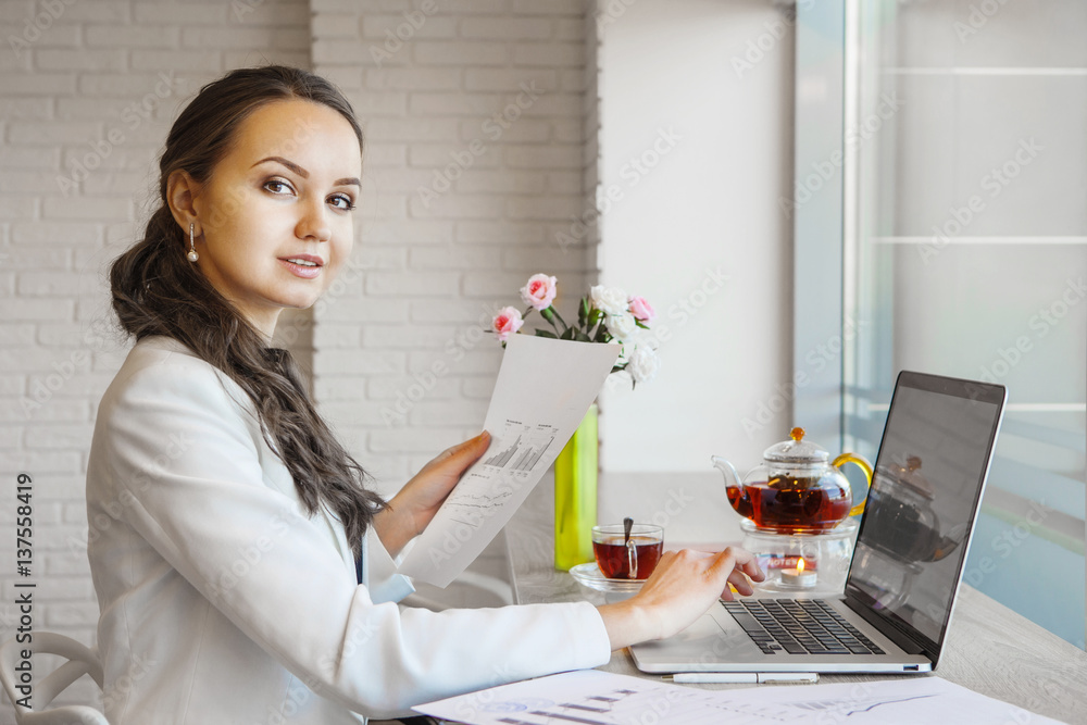 Confident woman holding document in hand and typing on computer. Confident woman holding document in hand and typing on computer.