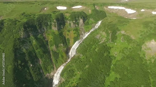 Mountain river flows into a waterfall. View of the waterfall from the bird's flight.