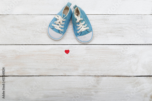 Blue shoes for a small baby on a wooden background. View from above