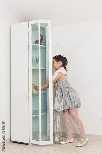 Young child girl opening cupboard door