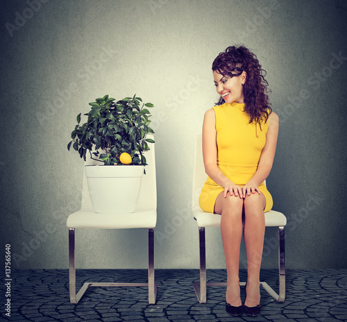 beautiful woman sitting on chair looking at lemon tree