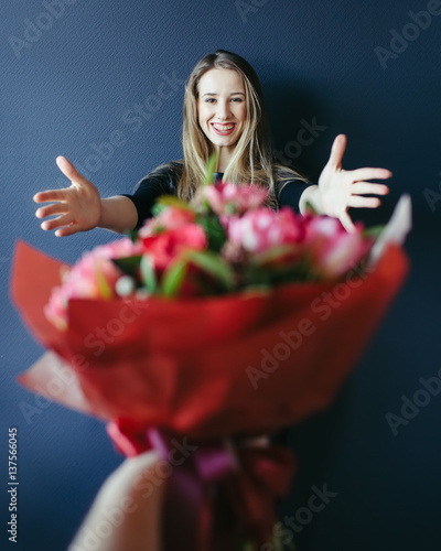 Cute girl getting bouquet of red tulips. Boyfriend giving tulips.