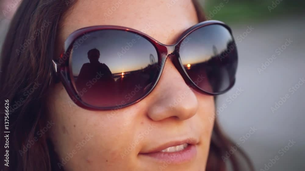 The young pretty woman watch through glasses at the sun by the sunset sky backgroud. 1920x1080 The young pretty woman watch through glasses at the sun by the sunset sky backgroud. 1920x1080