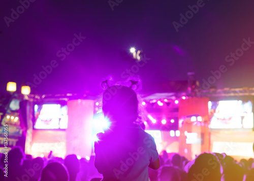 Blurred Youth Music Festival of pop music. Laser show on the stage. The crowd of fans. Silhouette of a little girl sitting on dad's shoulders. Blurred bokeh basic background for design