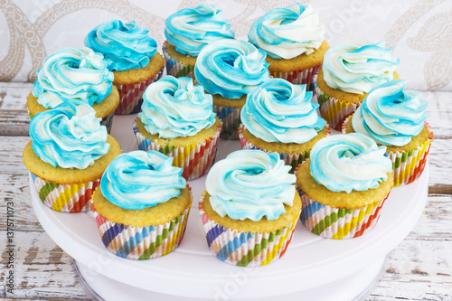 Festive cupcakes with cream in blue on a white wooden background