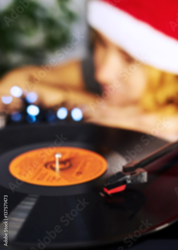 Blurred Image of Christmas. Gramophone playing a record. Blurred a girl in a Christmas cap with red hair listening to a vinyl record in the background 