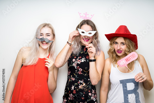 Obraz na płótnie three happy young ladies girls strike a pose on white background photo booth with party props w salonie