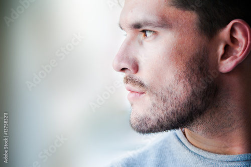 Handsome man looking forward and thinking. Close up portrait of caucasian man. Brunette on the blurry background