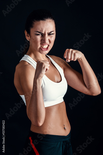 Angry fitness girl ready for fight on black background. © artyme