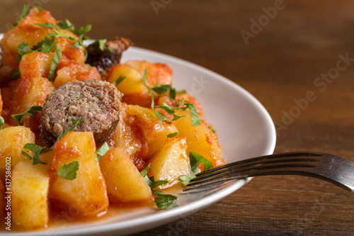 Potatoes stew with pork sausage and herbs on plate