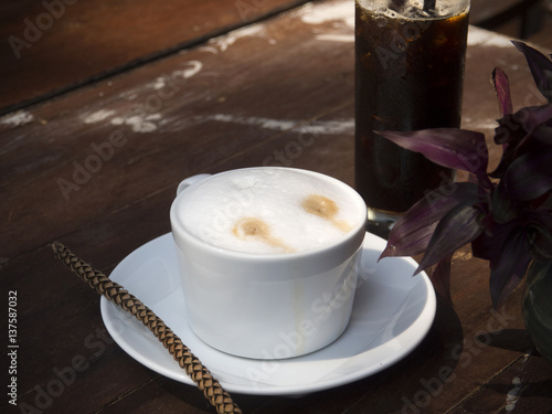 Hot cappuccino coffee and iced black coffee on wooden table photo