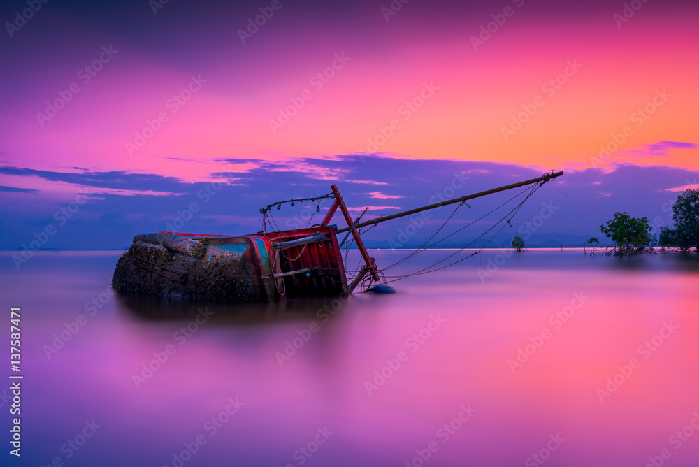 An old shipwreck or abandoned shipwreck, Boat capsized on beach in beautiful sunset background, Thailand.