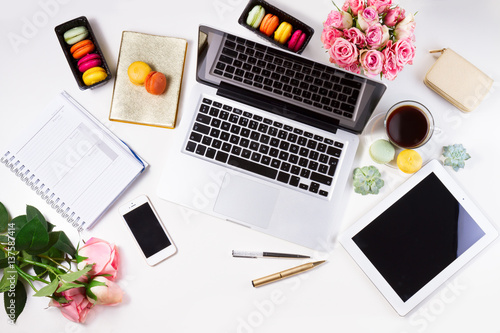 Feminine workspace with laptop, tablet and phone, top view