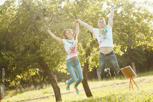 Smiling pretty couple jumping taking each other by the hand. Beautiful woman and handsome man having fun outdoors. Looking at camera