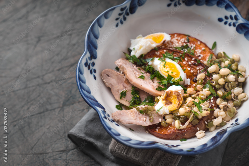 Salad with chicken, pumpkin, beans and quail eggs in a ceramic bowl Salad with chicken, pumpkin, beans and quail eggs in a ceramic bowl