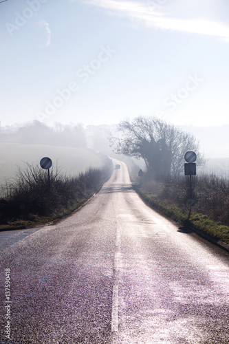 counrty road winding into distance on misty morning, road signs, countryside and mist photo