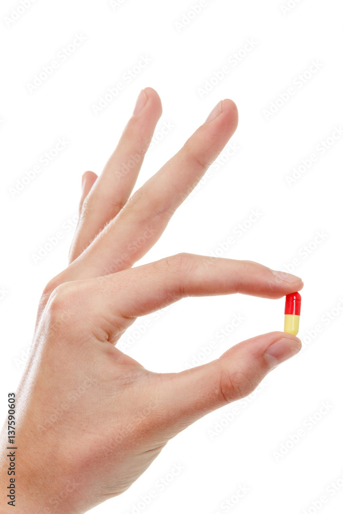 Hand holding a pill between thumb and forefinger Hand holding a pill between thumb and forefinger