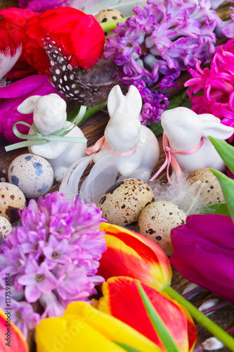 Spring fresh flowers with easter eggs and three white pocelane rabbits