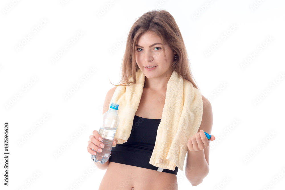 Fitness girl stands up straight and holding a towel on his shoulders water bottle isolated white background Fitness girl stands up straight and holding a towel on his shoulders water bottle isolated white background