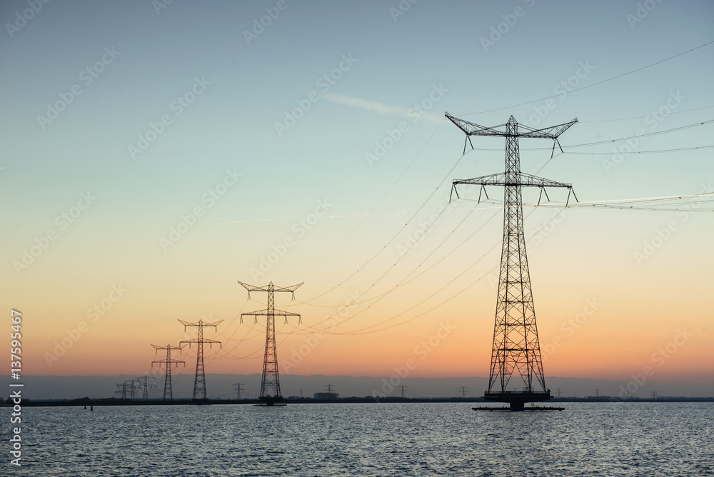 Electric poles in the water at sunset