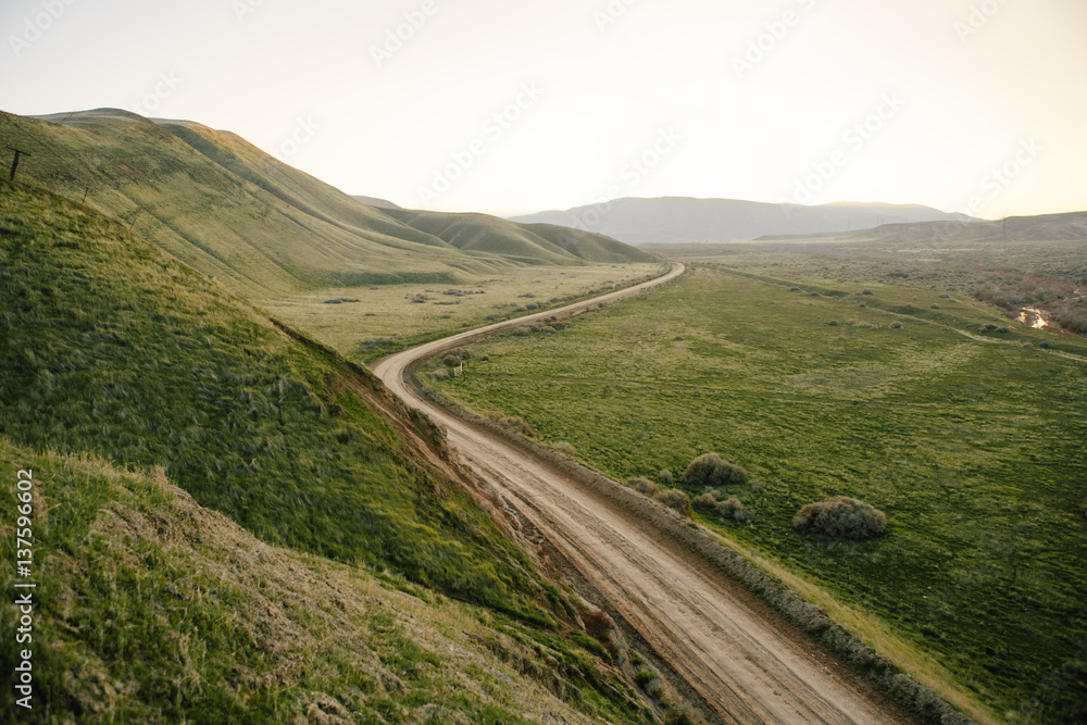 View of dirt road passing by mountain