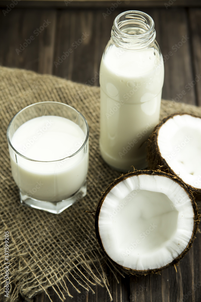 coconut milk in a glass next to the split in half coconut on sacking coconut milk in a glass next to the split in half coconut on sacking