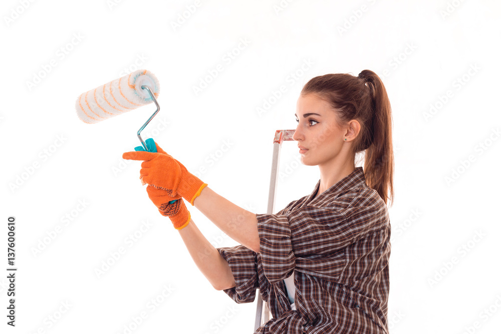 portrait of young concentrated brunette building woman with paint roller in hands makes renovation isolated on white background portrait of young concentrated brunette building woman with paint roller in hands makes renovation isolated on white background