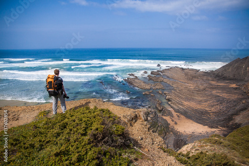 Tourist with backpack on the edge of a beautiful cliff near the ocean Portugal Algarve