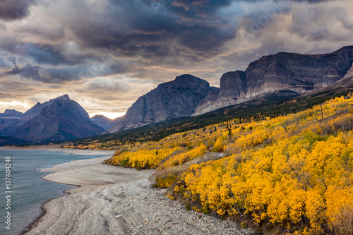 Dramatic sky in Autumn in Glacier National Park, Montana, USA. fall foliage in peak color on the shore of lake sherburne photo