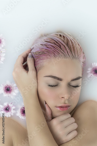 Woman beauty spa and wellness treathment with  flowers in bath with milk photo