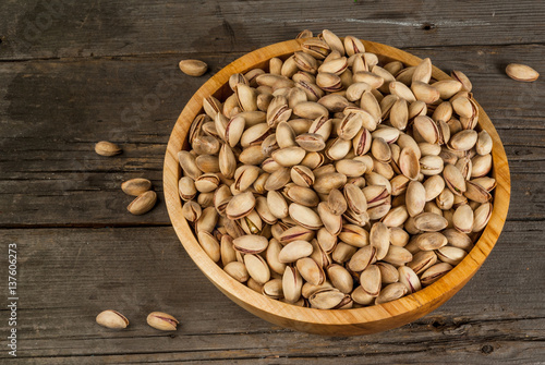Pistachio nuts in a wooden bowl on a rustic wooden table