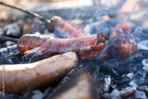 Sausages roasting on burning embers outdoors