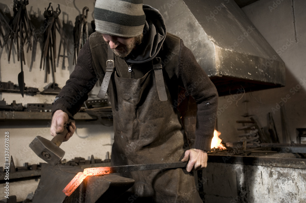 Blacksmith hammering metal on an anvil, Landshut, Bavaria, Germany Blacksmith hammering metal on an anvil, Landshut, Bavaria, Germany