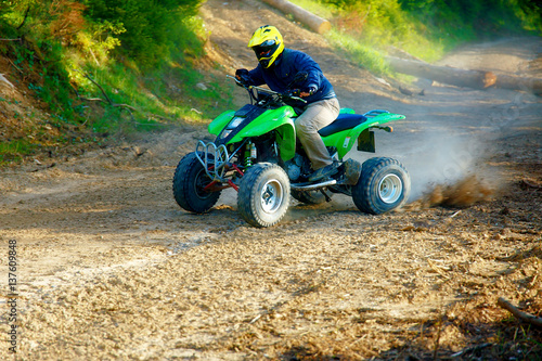 racer with yellow helmet on green quad enjoying his ride outdoors.