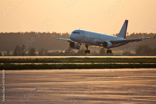 Plane is landing at sunset. Passenger commercial air transportation. Mid-range aircraft. Spotting in the airport.