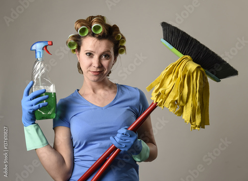 Obraz na plátně housewife stereotype hair rollers and washing gloves holding mop broom and deter