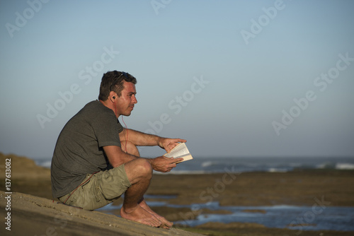 Man with Earphones and Book by Ocean