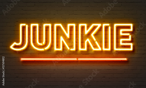 Junkie neon sign on brick wall background.