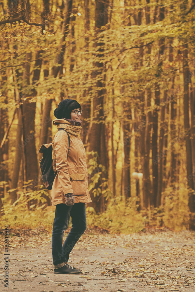Fototapeta premium Young stylish hipster girl standing in the autumn park and smiling