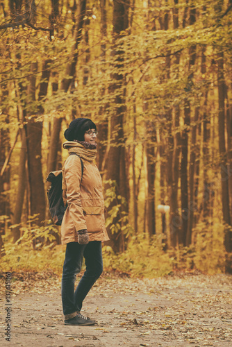 Young stylish hipster girl standing in the autumn park and smiling