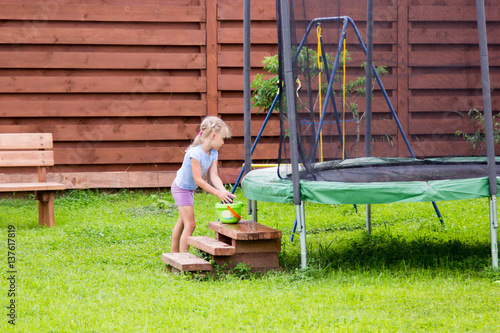 little girl washes her trampoline in backyard